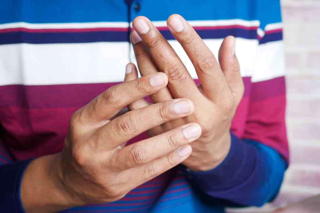 Person holding one hand in the other, indicating discomfort.