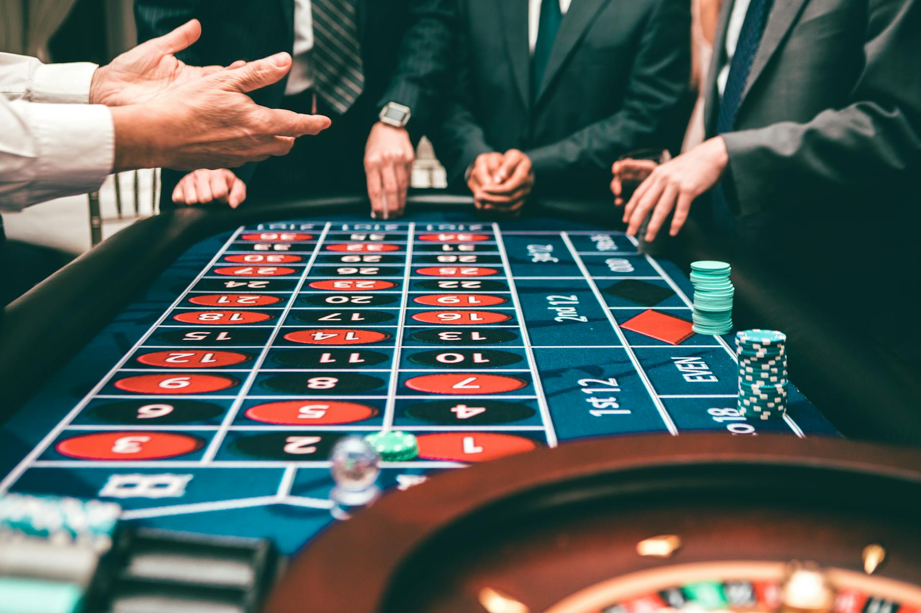 A picture showing the torsos and arms of people in suits as they gamble at a casino table.