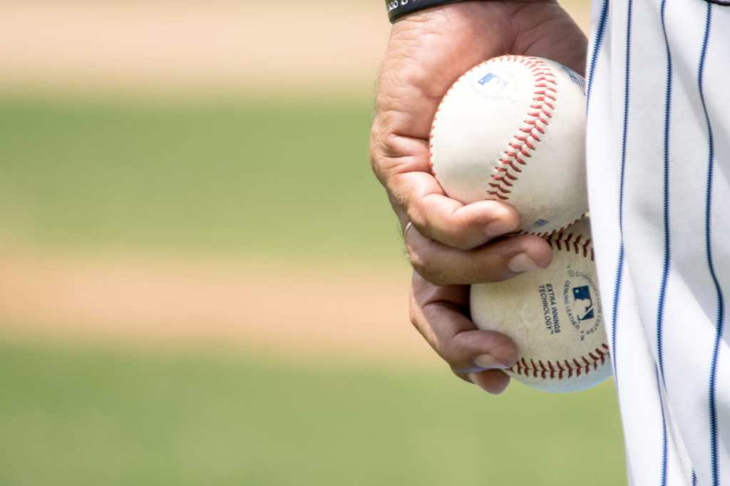 man holding two baseballs